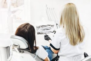 Dentist showing x-ray for the patient and explaining plan of tre