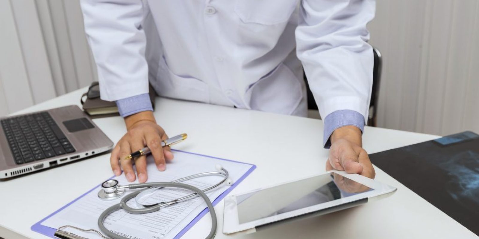 Doctor working with tablet computer at desk. Technology and medical concept.