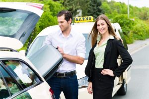 Young businesswoman in front of taxi with luggage