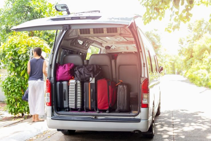 Van with luggage on a sandy with woman in blur backgroung travel