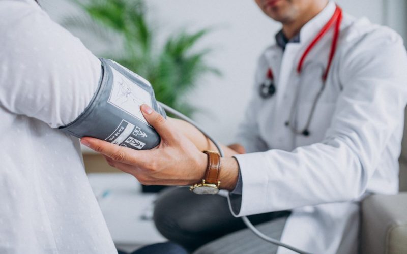 Young male psysician with patient measuring blood pressure