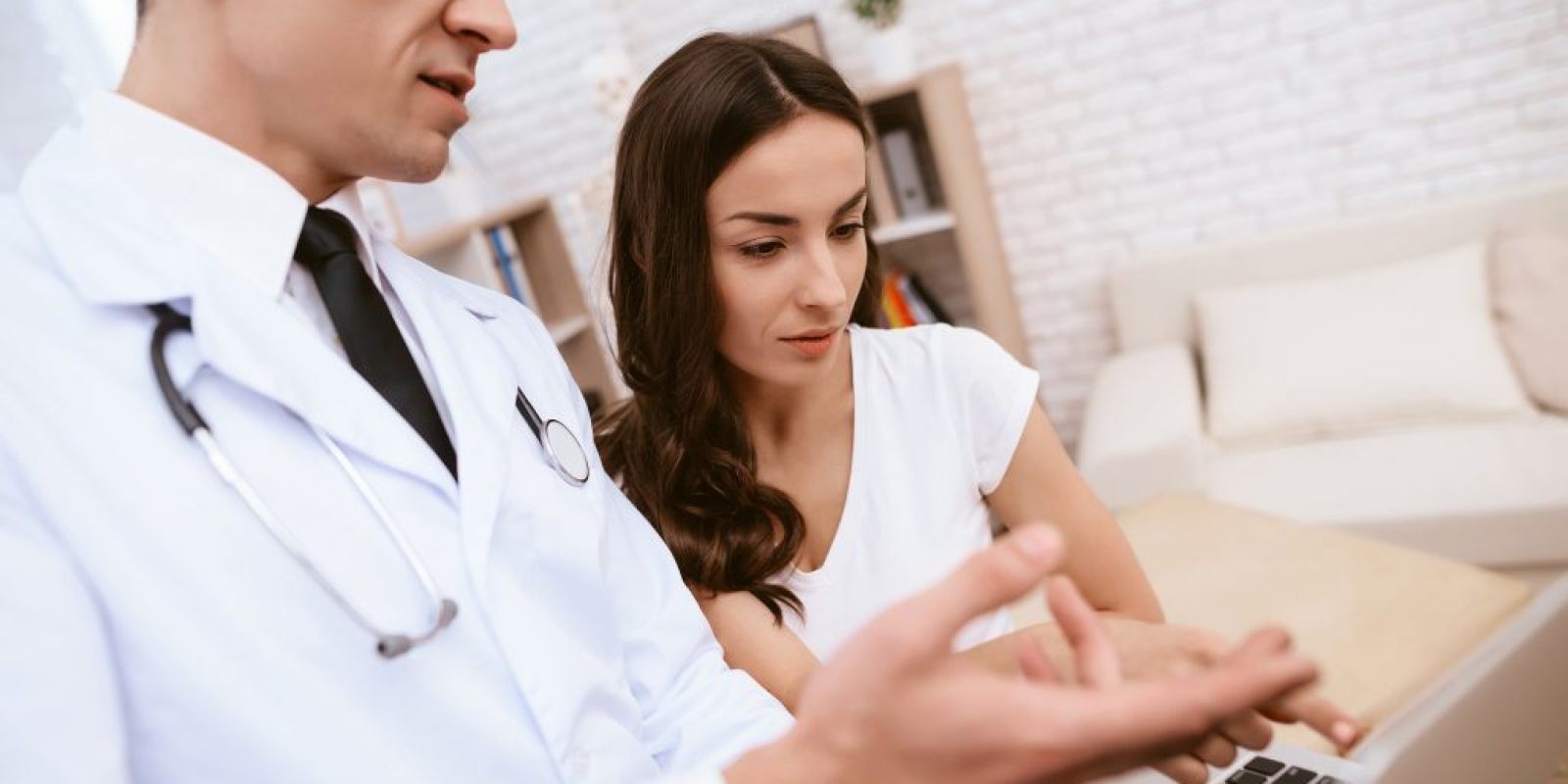Doctor is showing something on laptop to a pregnant girl.