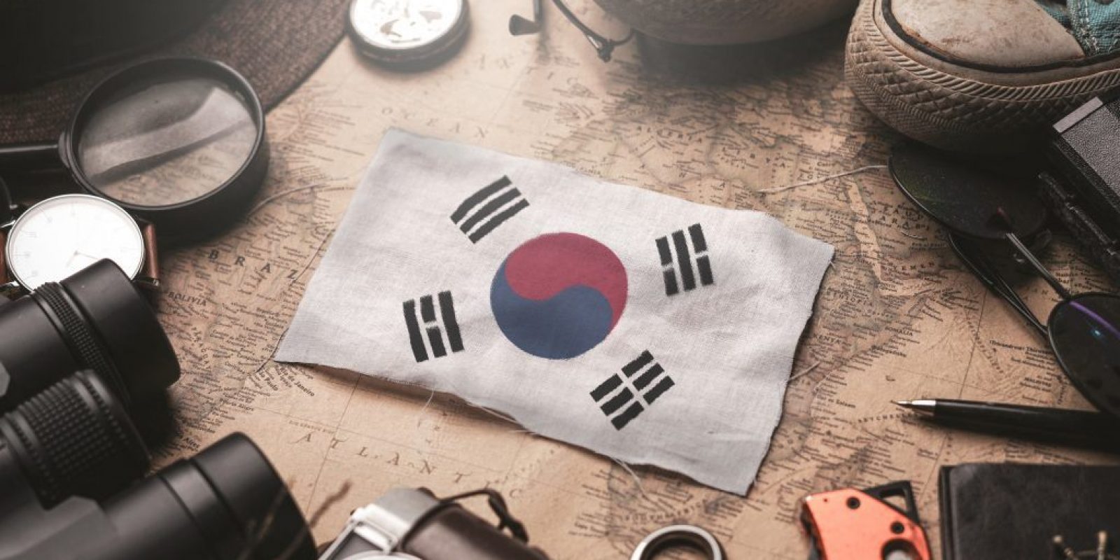 South Korea Flag Between Traveler's Accessories on Old Vintage Map. Tourist Destination Concept.